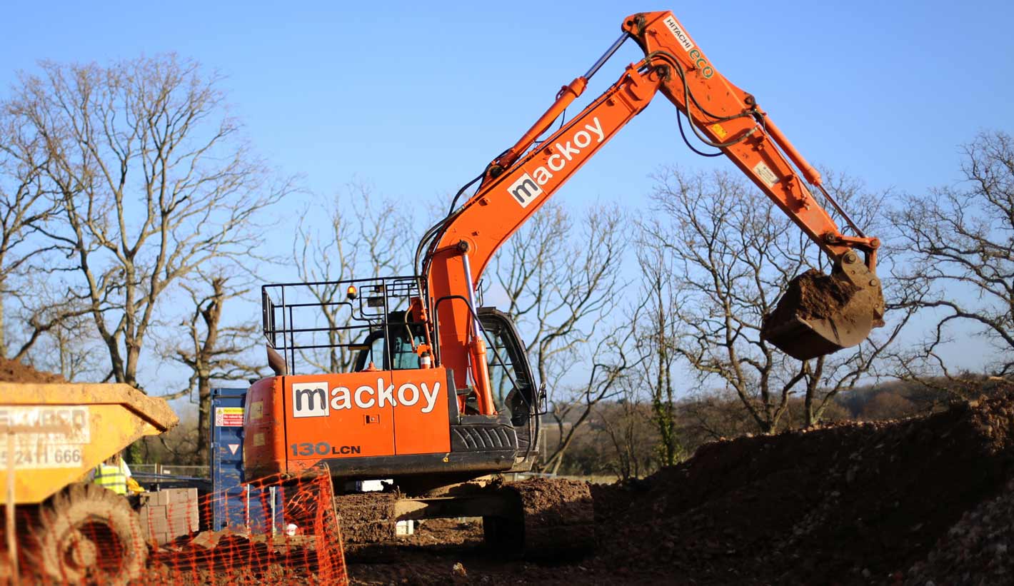 Mackoy Plant Machinery orange Excavator digging on site for new Bellway Contract in Fair Oak near Eastleigh